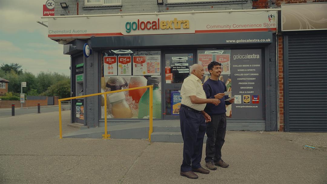 Still from Shop Dada: Darshan and his grandfather stand outside a convenience store, engaged in conversation.