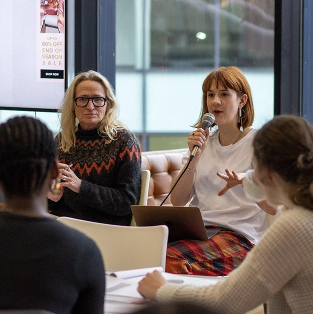 A person with a microphone speaking to a group of people