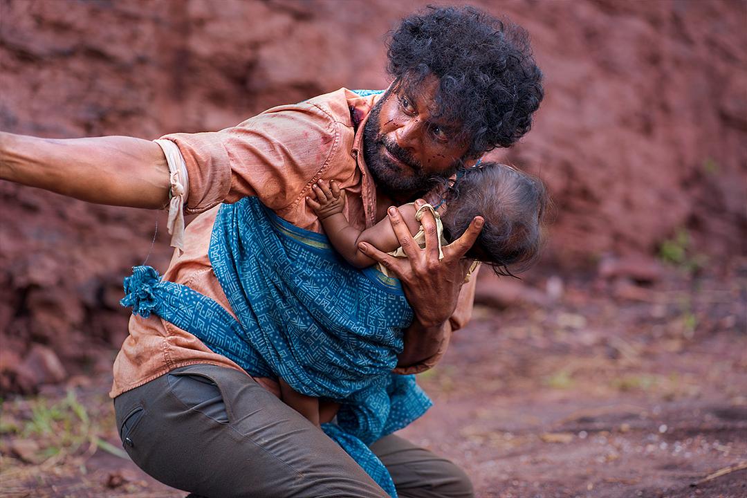 Dasru, bloodied and panicked, cradles his baby in a scene from JORAM