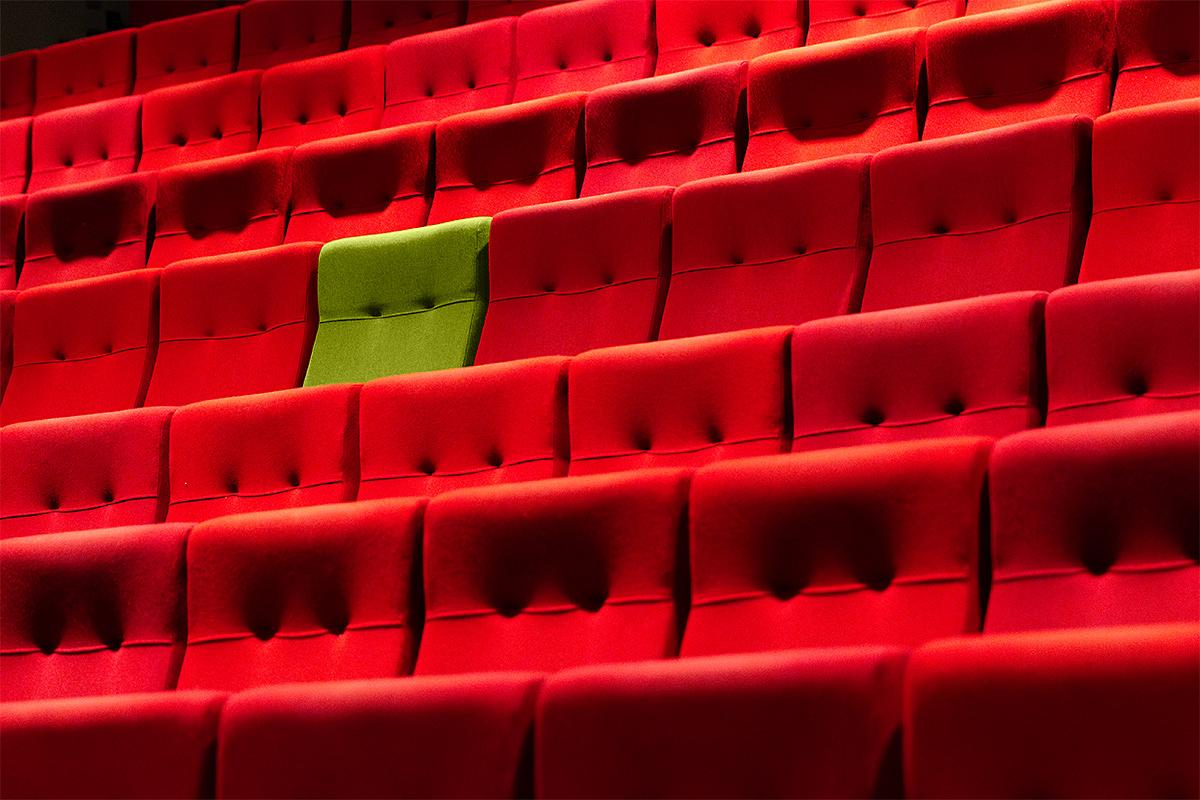 A green cinema seat stands out in a red auditorium