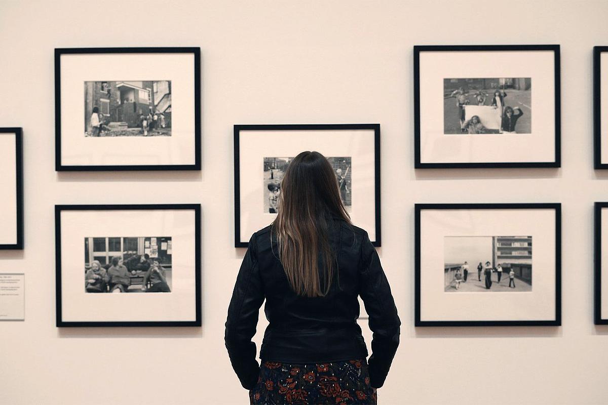 A woman is seen from behind looking at photographs in a Tish Murtha exhibition - scene from TISH