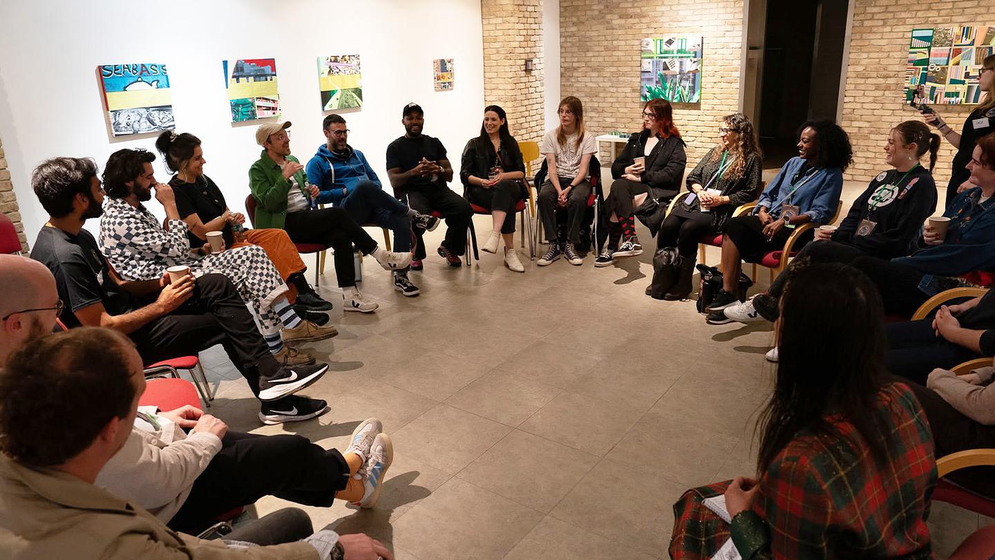 A group of people sit in a circle in an art gallery.
