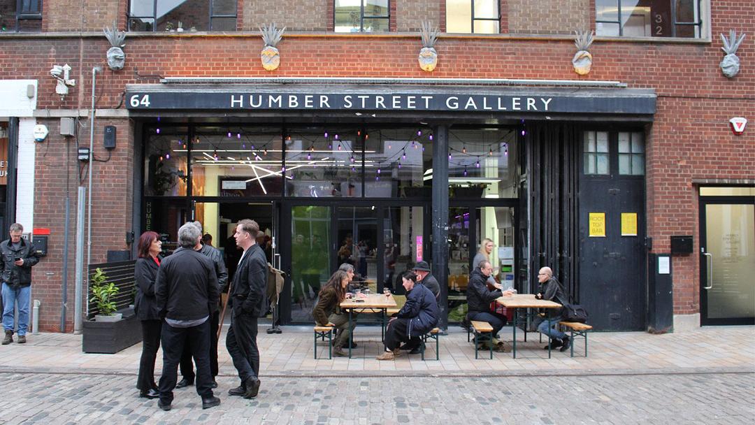 Exterior photograph of Humber Street Gallery: people gather and eat outside the brick building.