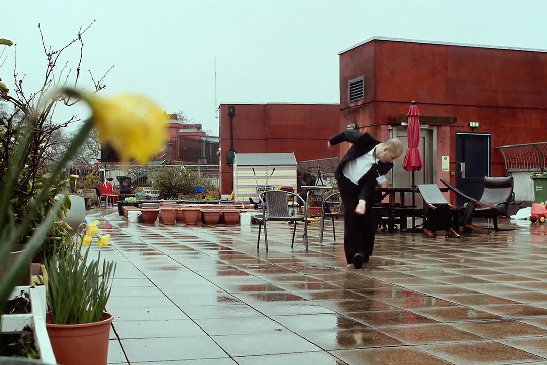 An office worker dances on a rooftop in a scene from SAUDADE