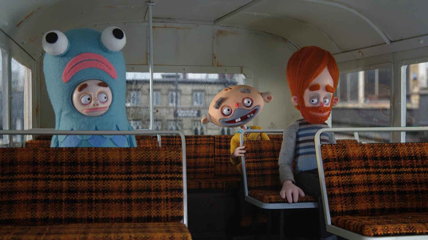 Still from Bernard shows three clay stop-motion figures seated inside a bus: one is dressed in an octopus costume.