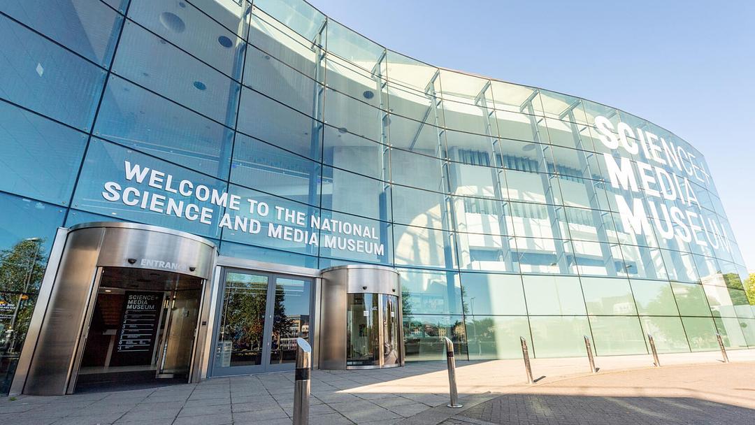 Exterior photograph of the National Science and Media Museum in Bradford.  The building is modern with a curved glass façade and the museum's name is displayed in large, white lettering. 