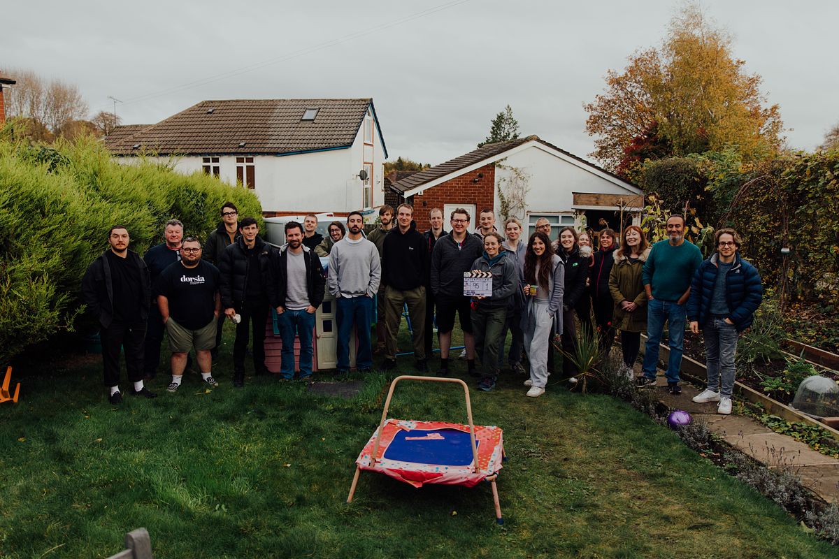 The crew working on the short film standing for a group photo in a back garden